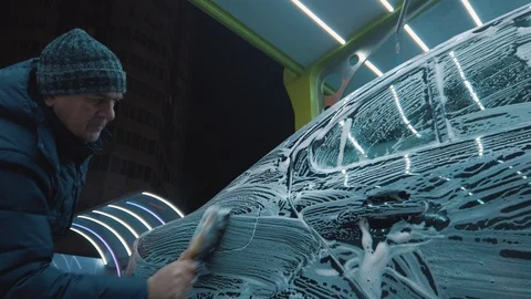 Man pushing a car surface with a dry rag outdoor at the evening. Cold weather. 库存影片 121853205