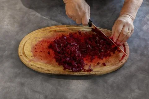 Man Pushing Chopped Beetroot Across Red Stained Oval Wooden Cutting Board Stock Photos