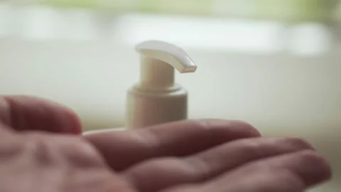 Man pushing dispenser and liquid soap squeezed out to hand, closeup. Stock Footage 131360072