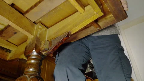 A man pushing in the extra leaf from an extending dining table. Stock Footage 300871347