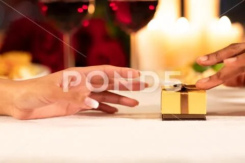 Man Pushing Gift Box To Girlfriend On Restaurant Table, Closeup