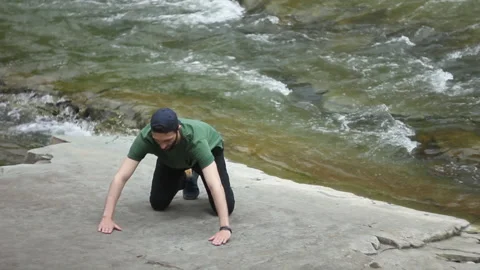 Man is pushing up from the ground by the river stream. Male doing sport exercise Video stock 130857931