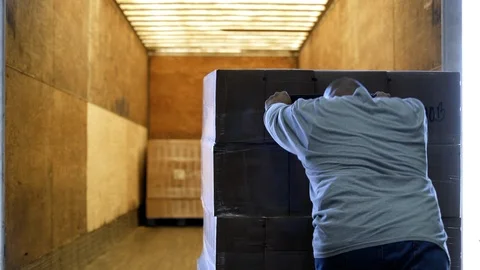 Man pushing heavy stock into elevator by hand operated pallet truck. Stock Footage 88027876