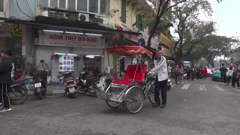 A man pushing his empty red trishaw around a street corner Stock Footage 272284771