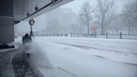 A man pushing snow blower in the road and snow flies after heavy snowstorm in Stock Footage 112165578