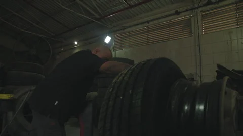 Man pushing a tire in a warehouse Stock Footage 275075214