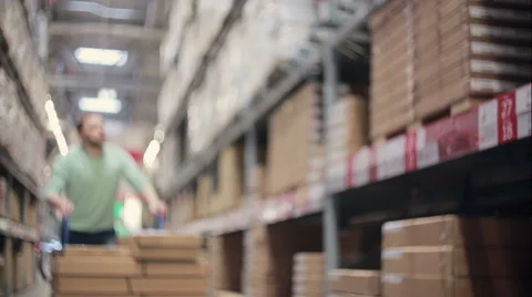 A man is pushing a trolley between shelves with cardboard boxes in a storage Stock Footage 66199026