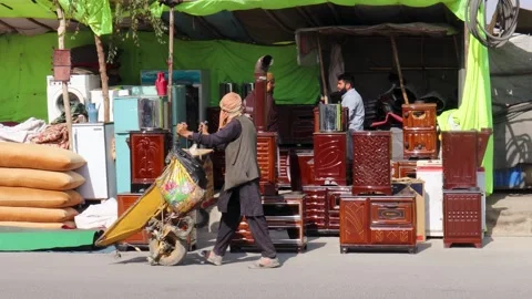A Man Pushing Wheelbarrows Through Kabul City, besides outdoor market bazaar Stockbeeldmateriaal 327781004