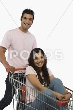 Man pushing a woman sitting in shopping cart Stock Photos