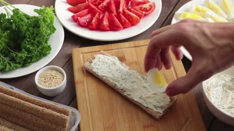Man put boiled egg and fresh tomato on  crispbread  making healthy sandwich Stock Footage 125460567
