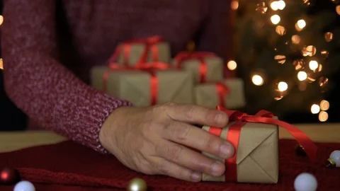 A man put Christmas gift boxes on table with bokeh lights background Stock Footage 94756500