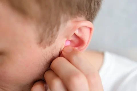 The man put the earplug in his ear. Blurred background Stock Photos