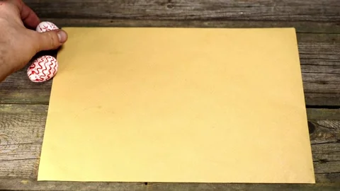Man put on of easter eggs with folk  pattern on edge of sheet of paper Video stock 127887149