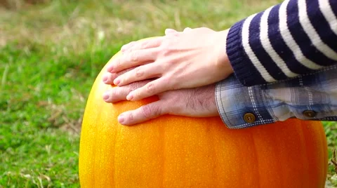 Man put hand on bright orange pumpkin, woman palm touch softly over Stock Footage 68169059