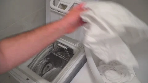 Man put laundry into washing machine Stock Footage 144962501