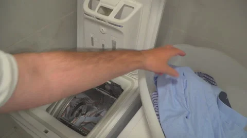 Man put laundry into washing machine Stock Footage 144962813