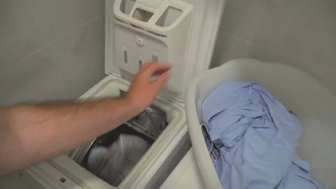 Man put laundry into washing machine Stock Footage 144962962