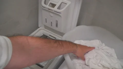 Man put laundry into washing machine Stock Footage 144964944