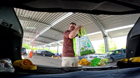 Man put packages in car trunk at groceries store parking Vídeos de archivo 247460227