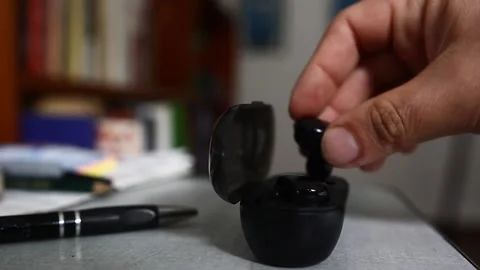 A man put a pair of wireless head phones back in the charging case Stock Footage 218641685