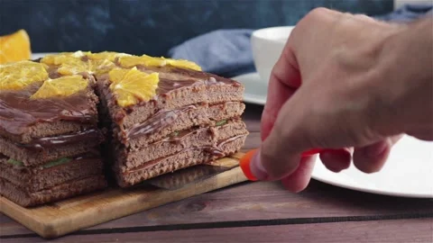 Man put piece of chocolate cake with orange on plate Stock Footage 111824465