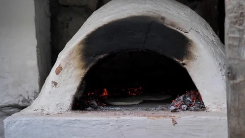 The man put the raw flatbread on a wooden spatula and put it in the oven. Stock Footage 126138810