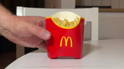 Man put in red paper bag with McDonald's logo with fresh French fries on table Video stock 343683568