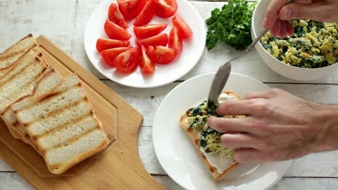 Man put spinach scrambled eggs  on bread making healthy sandwich for breakfast Stock Footage 241127332