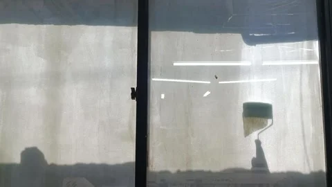A man put a thick layer of paint on a glass window for blocking sunlight or for  Stock Footage 327876956