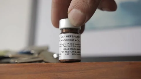 A man put a vial with reference standard material from ascorbic acid also known  Vídeos de archivo 209712896