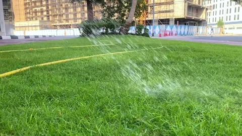 Man put water in the grass outside in the building area Vidéo 276575685