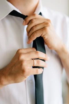 A man puts on and ties a tie while preparing for a wedding ceremony, close-up 스톡 사진