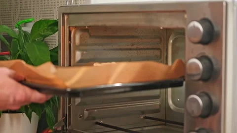 A man puts a baking sheet with raw pizza in preheated oven. Cooking homemade Stock Footage 244678249