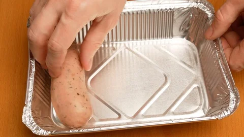 The man puts in baking tray sausages for roasting in the oven. Stock Footage 107730699