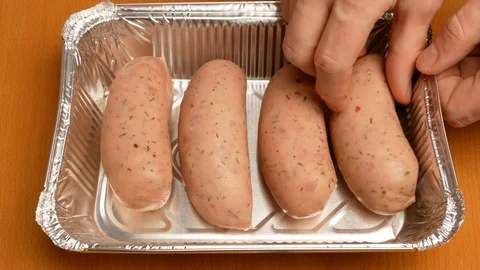 The man puts in baking tray sausages for roasting in the oven. Stock Footage 107730737