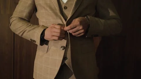 Man puts on beige jacket over vest with shirt Stock Footage 194729346