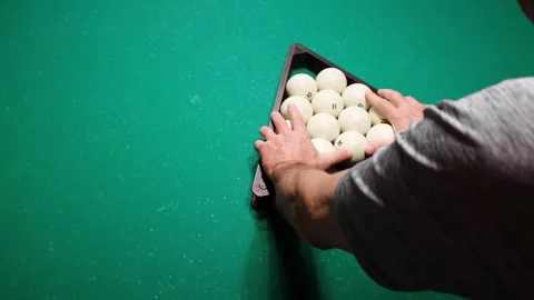 A man puts billiard balls into a triangle on a green pool table for a new game Stock Footage 293043753