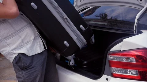 The man puts a black heavy suitcase with things in the trunk of the car. slow Stock Footage 87448634