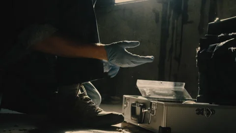 Man puts on blue plastic gloves kneeling by briefcase Stock Footage 275707627