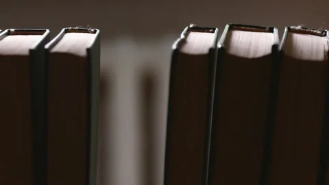 A man puts a book in its place in the bookshelf close-up. Inside view of a shelf Stock Footage 134507736