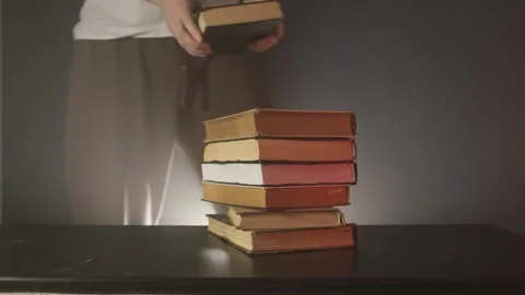 A man puts books on a table, a stack of textbooks, a guy puts books Stock Footage 264094237