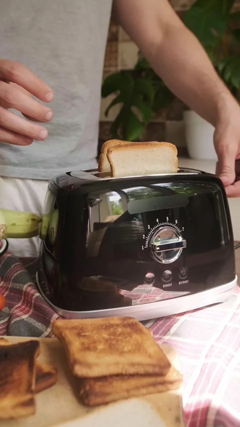 Man puts bread in toaster preparing healthy breakfast with avocado and Stock Footage 311864930