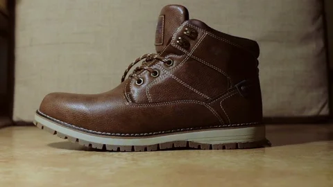  man puts on a brown leather boot on his leg (colour) Stock Footage 122251895