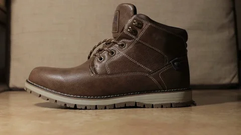  man puts on a brown leather boot on his leg Stock Footage 122253379