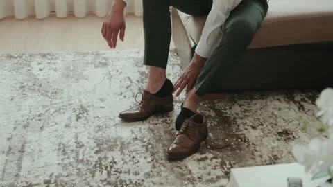 Man Puts on Brown Leather Brogues in Green Trousers Stock Footage 347058890