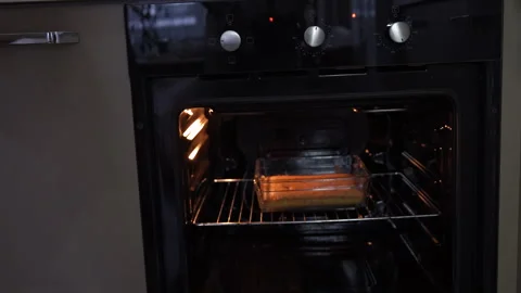 Man puts cake in oven Stock Footage 294884324