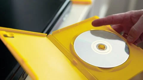 Man puts cd disc to a video player tray. Physical media concept.	 Stock Footage 301557000