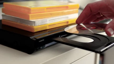 Man puts cd disc to a video player tray. Physical media concept.	 Stock Footage 301557084