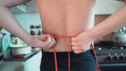 A man puts on a chef's apron before working in the kitchen Stock Footage 319830877
