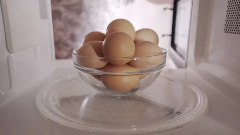Man puts chicken brown shell eggs inside microwave oven and turns it on Video stock 69181876